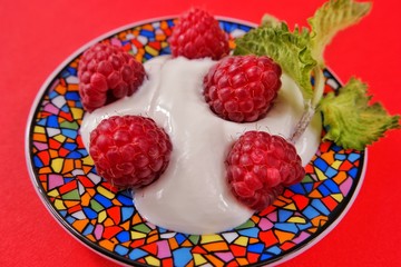 Large berry of raspberry on a multi-colored plate