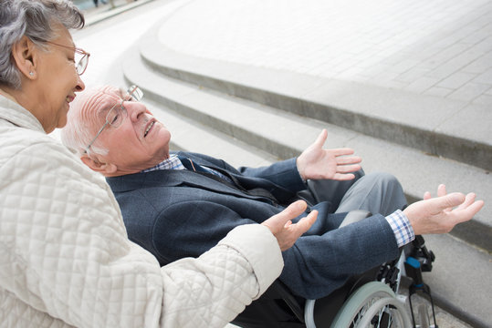 smiling senior woman talking to her husband in a wheelchair