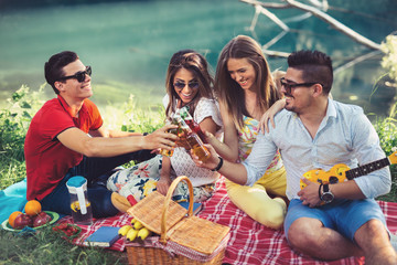 Young people having picnic near the river. Young friends relaxing by the river