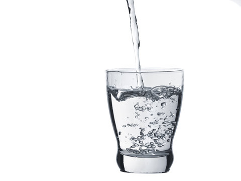 Water is poured into a glass isolated on white