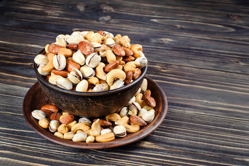 Mixed nuts in a bowl on a wooden background