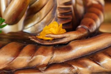 Gilded hand of Buddha holding flower, close up of temple statue from Thailand