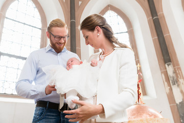 Fototapeta Junge Eltern mit ihrem Baby im Taufkleid in einer Kirche obraz