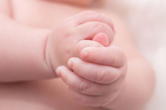 Newborn hands detail closeup. Lying on the bed and folding the hands