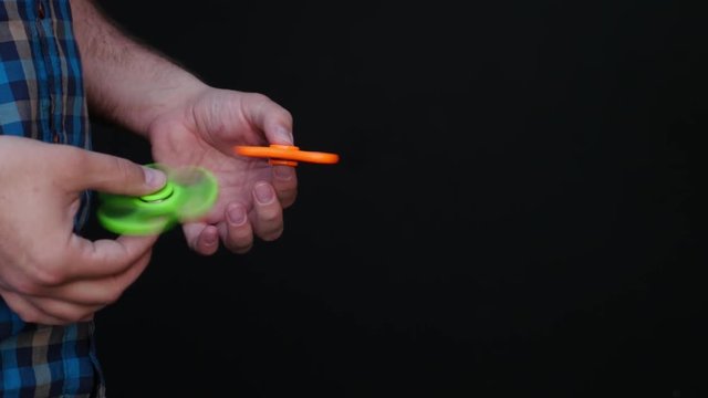 Footage of a person playing with two fidget spinners during a break at work, isolated on a black background...