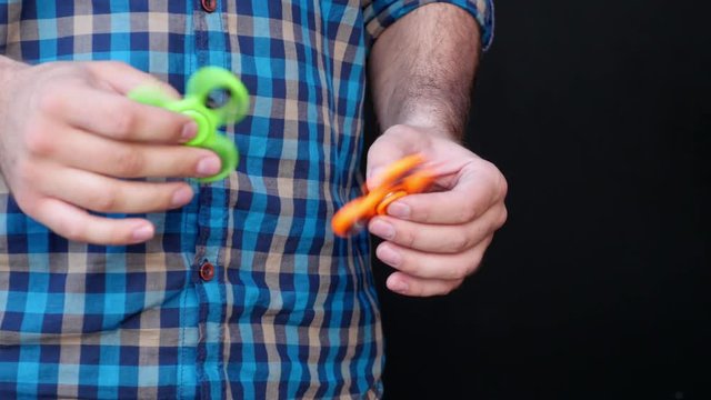 Footage of a person playing with two fidget spinners during a break at work, isolated on a black background...