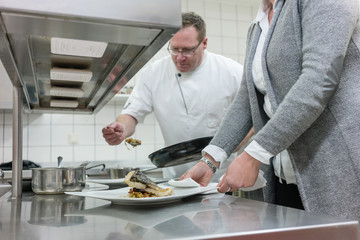 Kellnerin und Koch in Restaurant Küchen arbeiten gemeinsam 