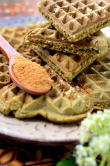 Homemade waffles with addition of matcha, pistachios, flax seeds. Decorated with coconut sugar.