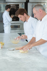 chef and apprentice preparing a cake together