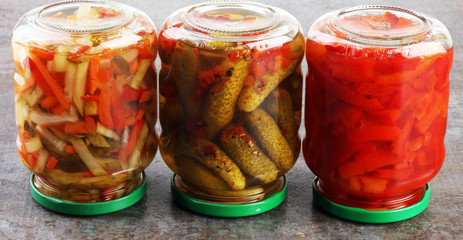 Jar with variety of pickled vegetables. Carrots, field garlic, cucumber in glas. Preserved food
