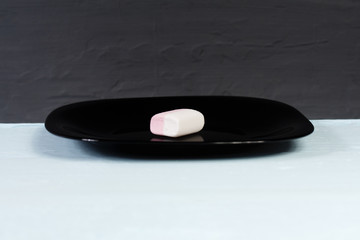 Obraz na płótnie Canvas Chewy marmalade. Soft striped candy on a black plate