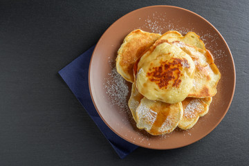 Top view: small pancakes with sugar powder and syrup
