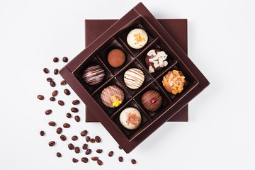 handmade chocolates in a square box and coffee beans near (top view)