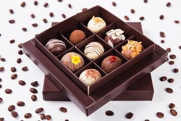 handmade chocolates in a square box and coffee beans around