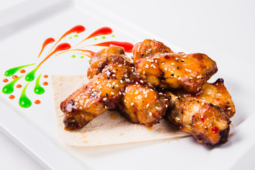 Fried chicken wings with sauce on a white plate (close)