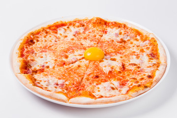 sliced pizza with egg yolk on a white plate on a light background.