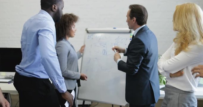 Brainstorming Meeting Of Businesspeople. Leader Business Man Explain His Ideas On White Board, Team Discussing New Plan In Modern Office Slow Motion 60
