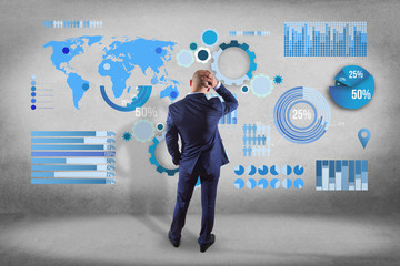 Businessman in front of a wall thinking about a business graph and chart interface - business concept