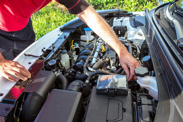 A man checks the engine by opening the car's hood