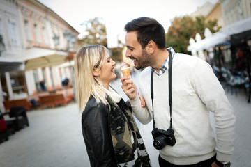 Happy young couple sharing ice cream on street