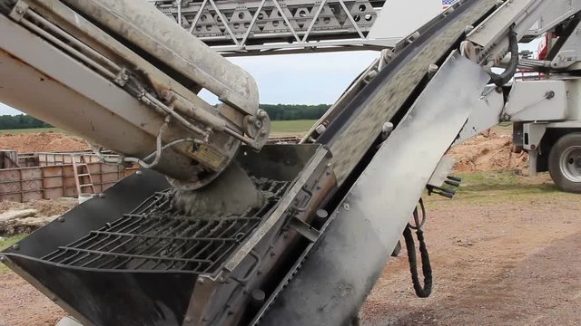 Cement truck unloading concrete on to a conveyor belt