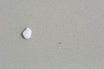 White pebbles, round small stones in a row on a wet white sand beach, space for letters or text