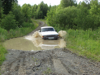 Obraz na płótnie Canvas Car overcomes deep puddles. Bad roads in the north of the Ural Mountains