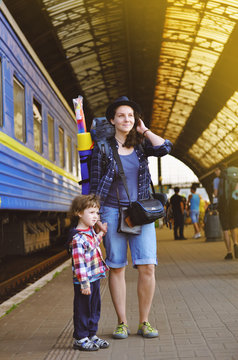 Mom and the baby are standing near the train