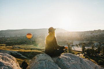 Young beautiful girl practicing yoga at the top of a mountain in Cappadocia at sunrise. Practices of relaxation.