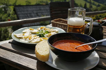 dumplings with onion, tomato cream soup and beer on wooden table