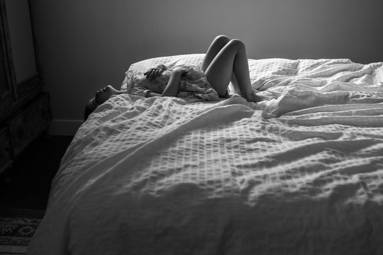 Young girl lying on top of bed, black and white 