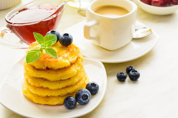 Cottage cheese pancakes with blueberries with jam and coffee on table