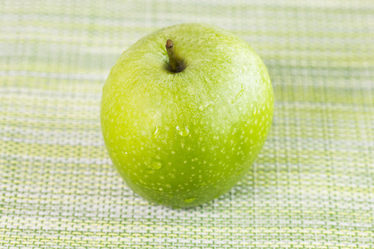 Green apple, isolated on green Hessian sack cloth woven background