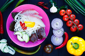 Thai soup with udon noodle, muer fungus and vegetables, top view on table decorated with various...