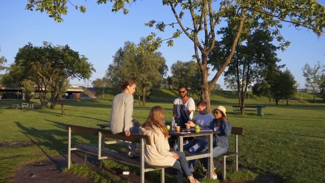 Multi-ethnic group of friends drinking coffee and chatting in a park