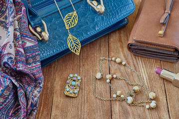 Women's accessories. Beautiful blue bag, scarf, necklace on a wooden background.