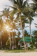 Love couple hugging under palm trees on the tropical beach