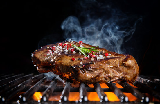 Beef steak on the grill grate, flames on background
