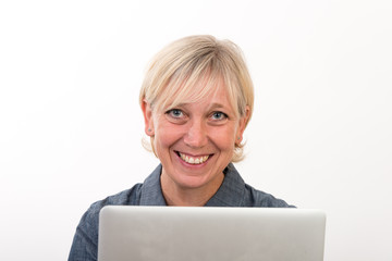 beautiful european mid aged woman working at a laptop - studio shot in front of light background