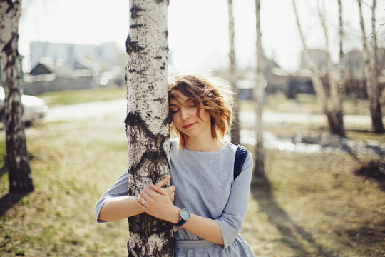 Young woman hugging Birch trees. Spring. Sunny worm day, enjoying outdoor