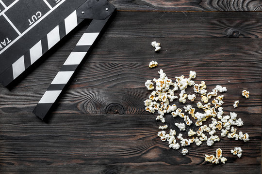 Watching the film. Movie clapperboard and popcorn on wooden table background top view copyspace