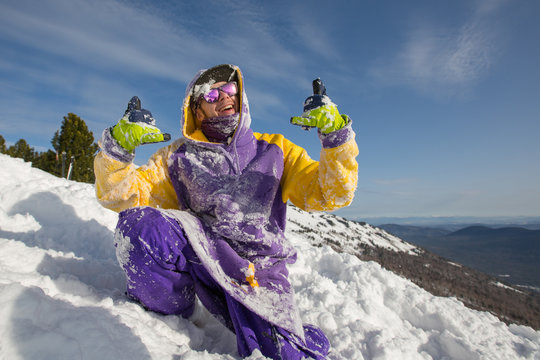 Guy have fun and playing on snow mountain top, showing thumbs up. Snowboard, freeride and winter holiday