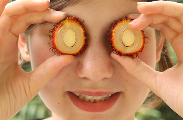 teenager girl with rambutan cut circle fruit close up photo