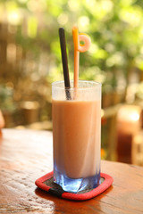 sappodila milk shake close up photo with straw on green summer outdoor background