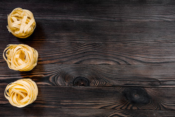Italian pasta fettuccine nest on grey wooden table top view copyspace