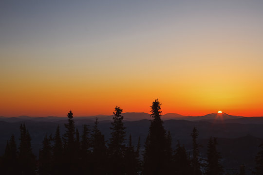 Red and orange sunrise above Siberian mountains in Sheregesh Ski resort