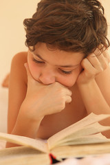 teen boy reading in bed on siesta close up photo