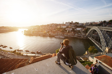 Travel photographer doing pictures of sunset above river in Porto, Portugal. Europe traveling