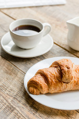 Office lunch with coffee, milk and croissant on wooden table background