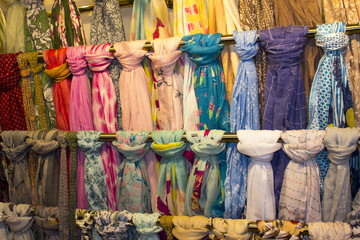 A colorful display of fashionable ladies scarves on hanging rails in a gift shop 